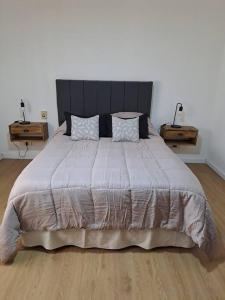 ein Schlafzimmer mit einem großen Bett mit zwei Endtischen in der Unterkunft Casa La Nona 5 personas con patio y quincho in Cordoba