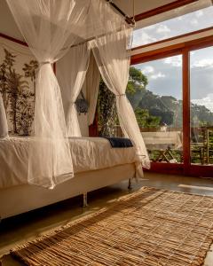 um quarto com uma cama de dossel e uma janela em La Luciole Ecolodge em Paraty