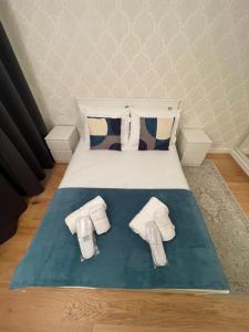 a bed with white towels and shoes on it at Sela House - Luton Airport in Luton