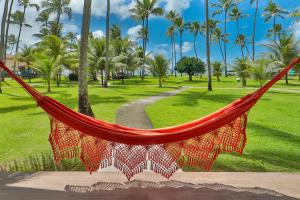 a red hammock in a park with palm trees at Pousada Xalés de Maracaípe in Porto De Galinhas