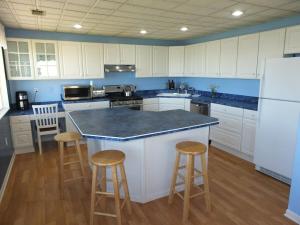 a kitchen with white cabinets and a island with bar stools at The Life Aquatic - Lakefront Kayaks Included! in Alpena