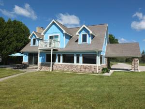 une maison bleue avec une terrasse sur une pelouse dans l'établissement The Life Aquatic - Lakefront Kayaks Included!, à Alpena
