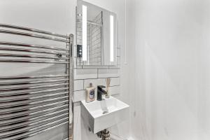 a white bathroom with a sink and a mirror at 5 Mins From Leeds - 4 Bed - Parking - Sleeps 9 in Leeds