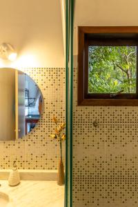 a bathroom with a mirror and a vase with flowers at La Luciole Ecolodge in Paraty