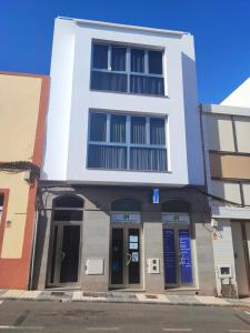 um edifício branco com portas azuis numa rua em EL INGENIO em Ingenio
