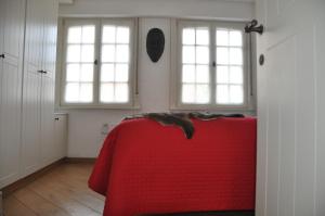 een kamer met een rode tafel en twee ramen bij Vakantiehuis 't Verloren Schaap Damme in Damme