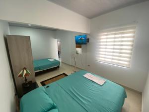 Un dormitorio con una cama azul y una ventana en IW-Apto en la vega, cerca al CC Viva en Villavicencio