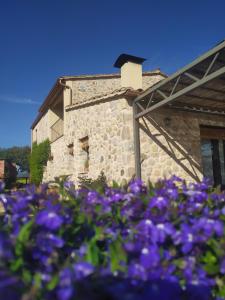 ein Steingebäude mit lila Blumen davor in der Unterkunft Can Parés in Sant Gregori