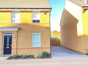 a brick house with a blue door on the side of it at Brand New Stylish 3 Bed House in Milton Keynes