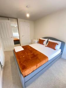 a bedroom with a large white bed with orange pillows at Brand New Stylish 3 Bed House in Milton Keynes
