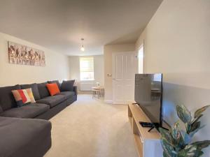 a living room with a couch and a tv at Brand New Stylish 3 Bed House in Milton Keynes