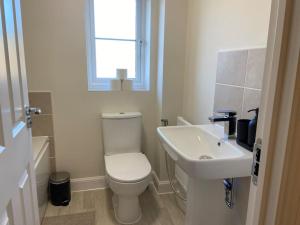 a white bathroom with a toilet and a sink at Brand New Stylish 3 Bed House in Milton Keynes