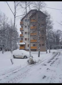 a building in the snow with a car parked in front at Apartman AS in Zlatibor