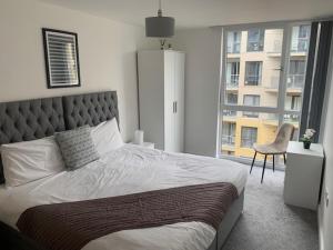 a bedroom with a large bed with a chair and a window at Beautiful Manchester 2 bedroom apartment in Manchester