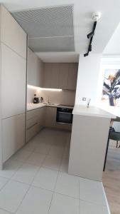a kitchen with white cabinets and a white tile floor at 37th Floor - SkyView Oasis - C in Skopje