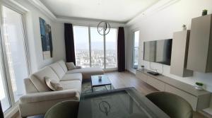 ein Wohnzimmer mit weißen Möbeln und großen Fenstern in der Unterkunft 37th Floor - SkyView Oasis - C in Skopje