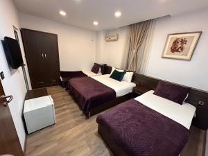 ein Hotelzimmer mit 3 Betten und einem TV in der Unterkunft Hotel Real in Pristina
