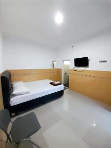 Hotel Srikandi Baru في يوغياكارتا: غرفة نوم بسرير وكرسي وتلفزيون
