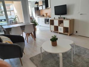 een woonkamer met een tafel en een televisie bij Magnifique appartement avec garage privé et terrasse in Reims