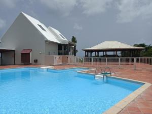 a large blue swimming pool with a gazebo at Chez Madeline in Le Gosier