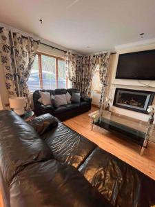 a living room with a leather couch and a television at Luxury Home in Dublin WiFi TV B&B Close to City Centre in Lucan