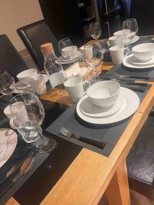 - une table en bois avec des assiettes blanches et des verres à vin dans l'établissement Luxury Home in Dublin WiFi TV B&B Close to City Centre, à Lucan