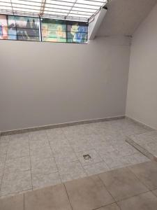 um quarto vazio com uma parede branca e piso em azulejo em Departamento de Caro em Tandil