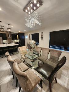 The Villa Orlando@College Park. Sleeps16 في أورلاندو: غرفة معيشة مع طاولة وكراسي زجاجية