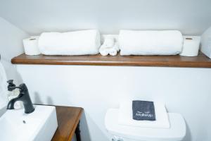 Baño con toallas en un estante sobre un aseo en Snodgrass Suite 301, Hyland Hotel en Palmer
