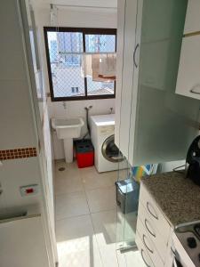 baño pequeño con lavabo y lavadora en Lindo Apartamento no Guarujá - Enseada, en Guarujá