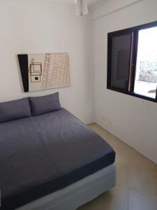 1 dormitorio con cama y ventana en Lindo Apartamento no Guarujá - Enseada, en Guarujá