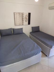 1 dormitorio con 2 camas con sábanas azules y una foto en Lindo Apartamento no Guarujá - Enseada, en Guarujá