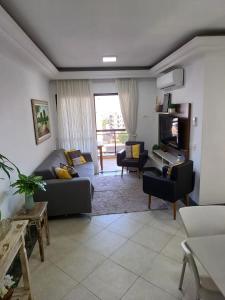 sala de estar con sofá y TV en Lindo Apartamento no Guarujá - Enseada, en Guarujá