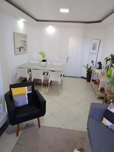 sala de estar con mesa y silla negra en Lindo Apartamento no Guarujá - Enseada, en Guarujá
