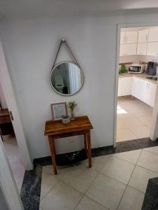 un pasillo con una mesa y un espejo en la pared en Lindo Apartamento no Guarujá - Enseada, en Guarujá