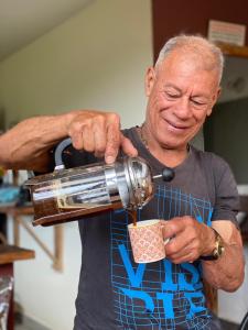 an older man is pouring coffee into a cup at Finca Momota Salento in Salento