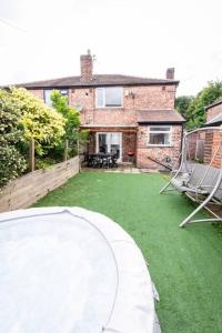 a house with a green yard with two chairs at Windsor House 3 Bedrooms Sleeps 8 in Manchester