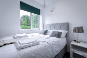 a bedroom with a large white bed with a window at Windsor House 3 Bedrooms Sleeps 8 in Manchester