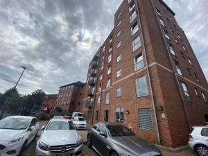 een bakstenen gebouw met auto's geparkeerd op een parkeerplaats bij Cute 2 bed flat in the heart of Derby By 20Property Stays Short Lets & Serviced Accommodation in Derby