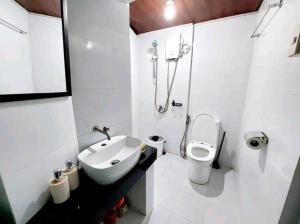 uma casa de banho branca com um lavatório e um WC em Simple Room in a Transient House em Baguio
