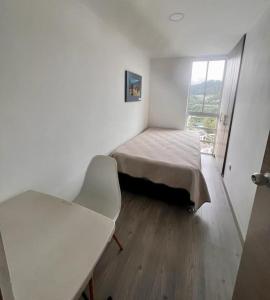 Zimmer mit einem Bett, einem Stuhl und einem Fenster in der Unterkunft Urban Manizales in Manizales