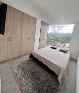 ein Schlafzimmer mit einem Bett und einem großen Fenster in der Unterkunft Urban Manizales in Manizales