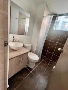 ein Badezimmer mit einem WC, einem Waschbecken und einem Spiegel in der Unterkunft Urban Manizales in Manizales