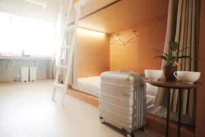 una habitación con una maleta, una cama y una mesa en Hostel Casa Noda en Nagasaki