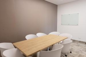 a conference room with a wooden table and white chairs at Distrito 90 in Barranquilla