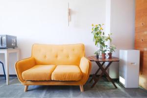 a yellow chair in a living room with a table at Hostel Casa Noda in Nagasaki
