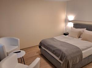 a bedroom with a bed and a white chair at Hotel Zum Postkutscher in Cottbus