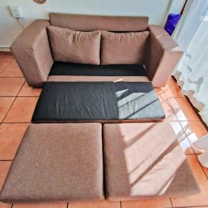 a brown couch sitting on top of a tile floor at Back to the 80s in Cape Town