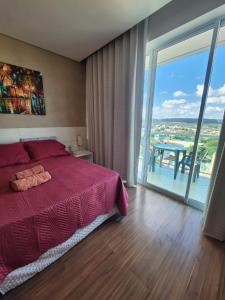 um quarto com uma cama vermelha e uma grande janela em Apto ótima localização, self check-in, wi-fi, varanda e vista linda - 401 em Lagoa Santa