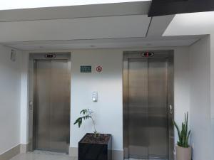 two elevators in an office building with a plant at Apto ótima localização, self check-in, wi-fi, varanda e vista linda - 401 in Lagoa Santa